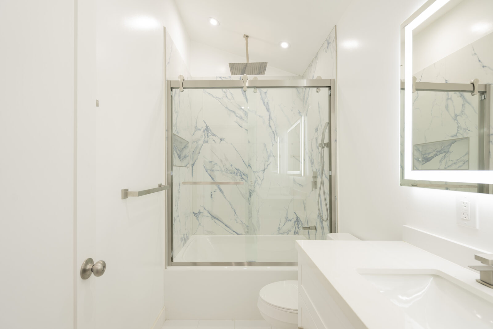 Bathroom tub and glass shower enclosure with blue-veined wall panels in the Thousand Oaks ADU