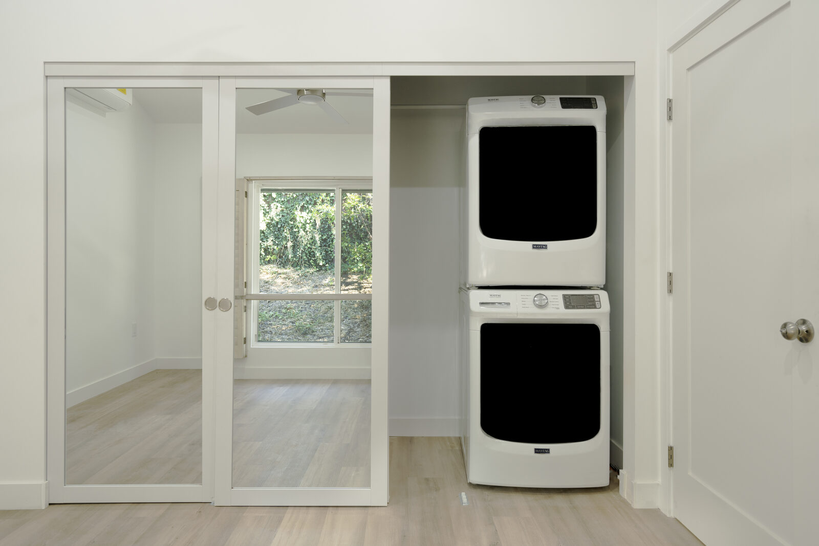 Stacked washer and dryer beside mirrored closet doors in the Thousand Oaks ADU bedroom