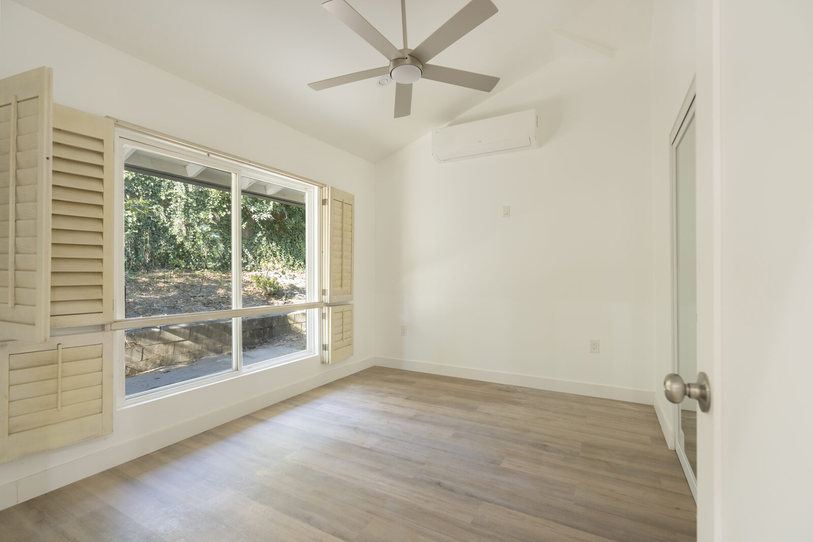 Bedroom with a large garden-facing window, ceiling fan, and mini-split in the Thousand Oaks garage conversion