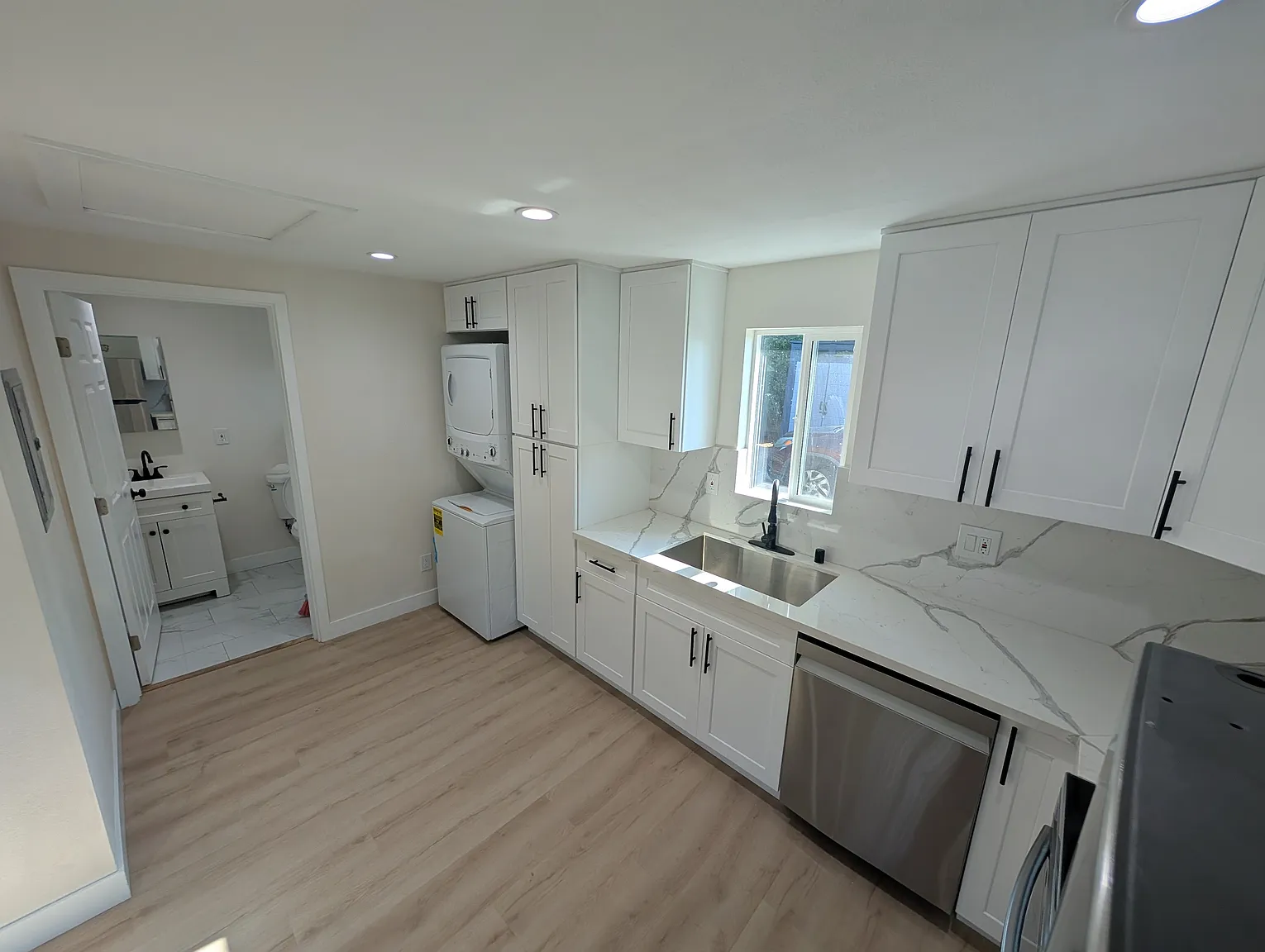 Full ADU kitchen and laundry area with stacked washer dryer, quartz counters, and efficient layout