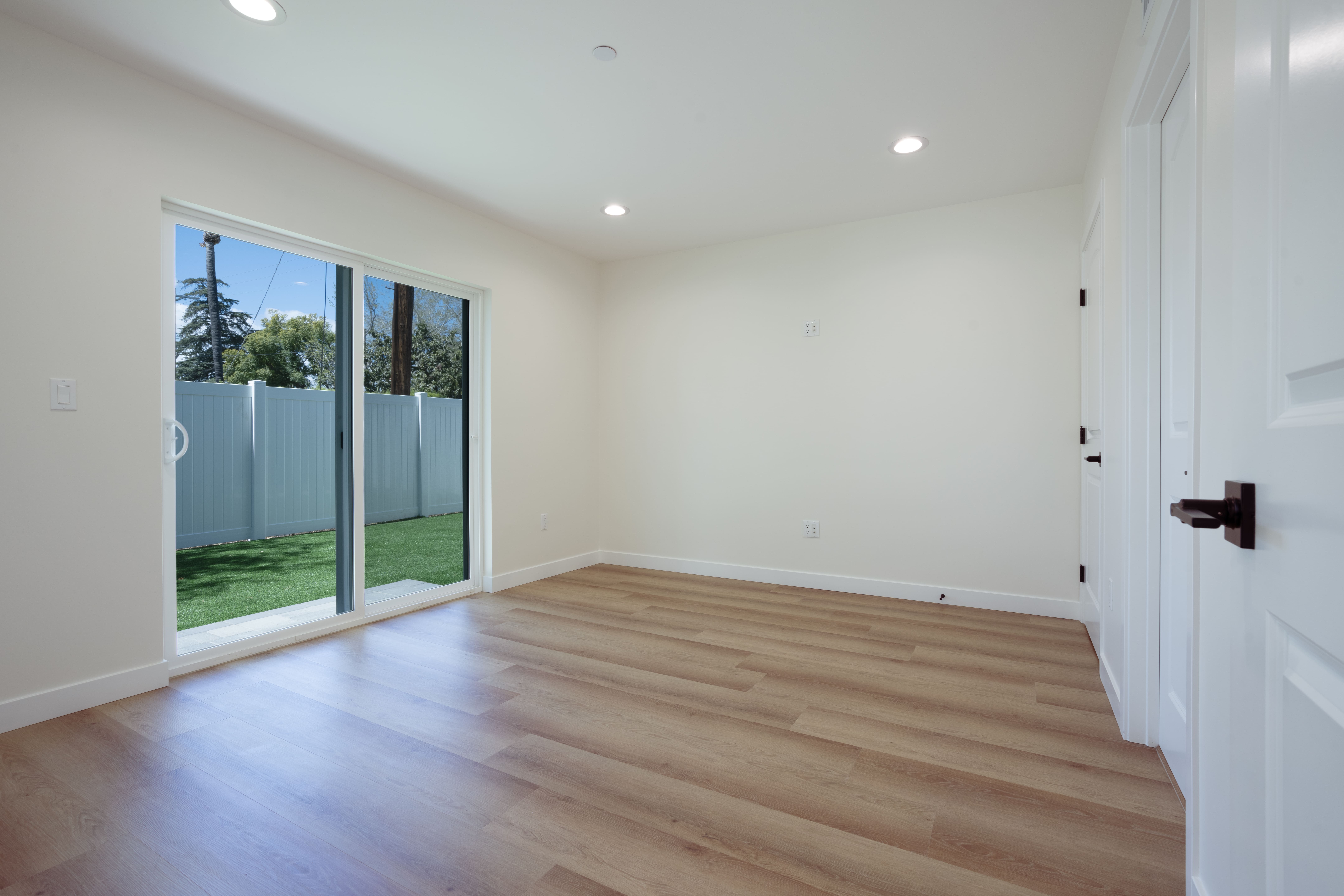 Spacious ADU living room with sliding glass doors opening to private backyard, light oak flooring